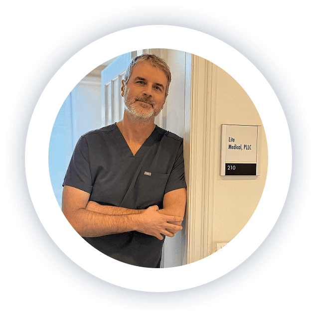 Lite Medical provider Dr. Kyle Kingsley in clinical scrubs standing at the entrance of the Lite Medical office suite.