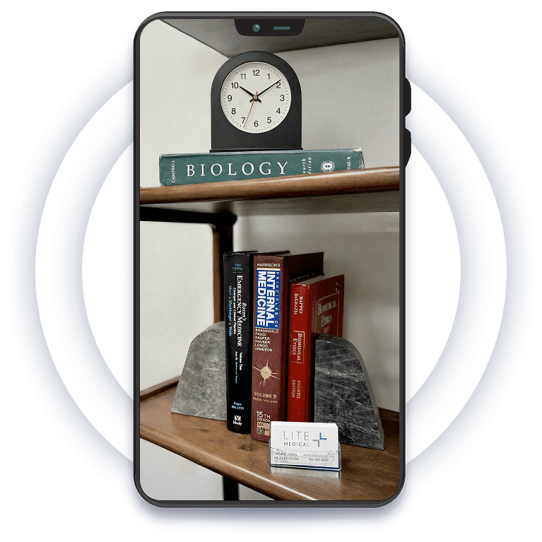 Medical textbooks, a desk clock, and Lite Medical business cards displayed on a bookshelf inside the clinic.